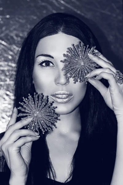 Young beautiful woman brunette with Christmas decorations silver snowflakes. Fashion make-up in cold shades. The Snow Queen. Black and white image.