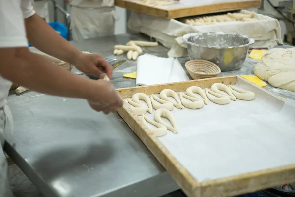 Bakers making Fresh Pretzels on Dough Covered Table