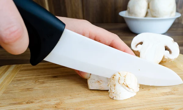 Cutting mushrooms on a cutting board with the knife