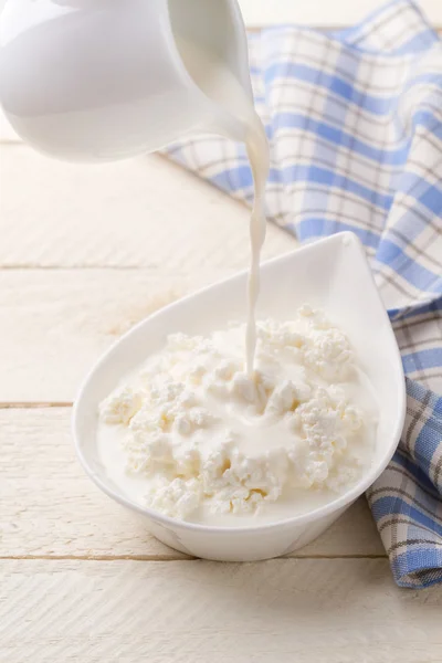 Pouring dairy cream in cottage cheese