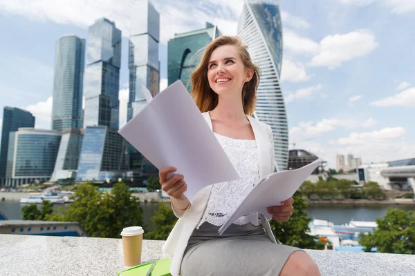Young smiling businesswoman with heap of papers