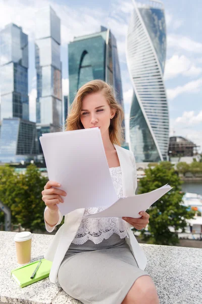 Young smiling businesswoman with heap of papers