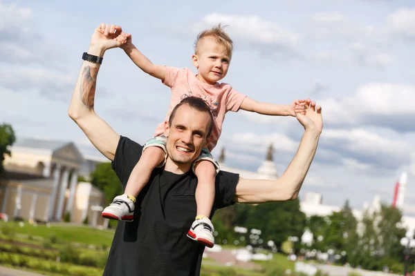 Son on the shoulders of his father in the park