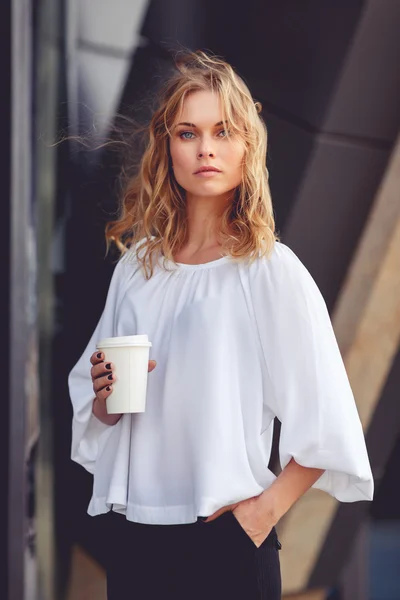 Business woman with wavy blonde hair holding coffee