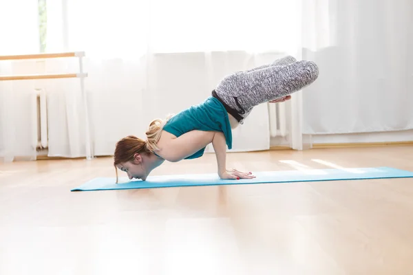 Flexible girl doing arm balancing mix exercises, lotus peacock position