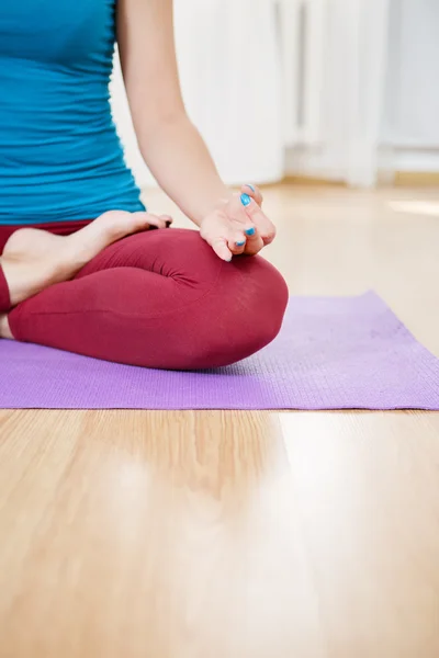 Woman in sportswear practicing yoga in living room, lotus asana