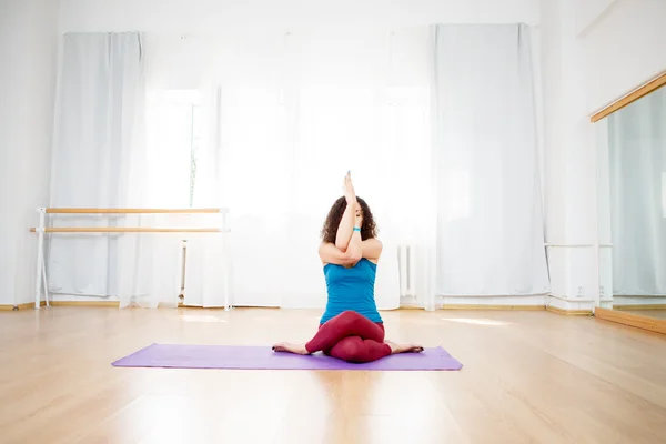 Woman doing yoga exercise with her arms and legs crossed