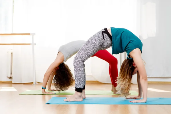 Two young girls doing back bend pose in yoga class