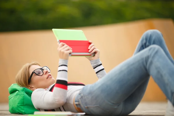 Young woman in glasses is lying on a wooden platform