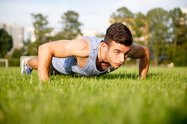 Young athlete doing push-ups on grass