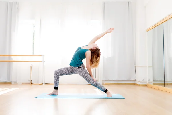 Flexible woman practicing high lunge pose in light spacious studio