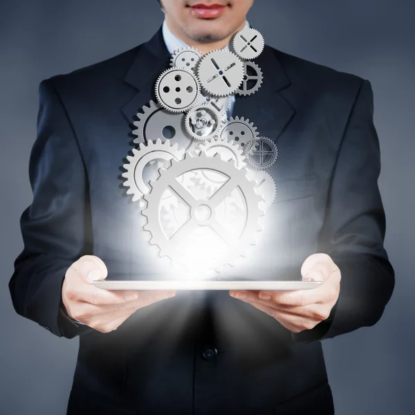 Businessman holding tablet showing gears, business concept