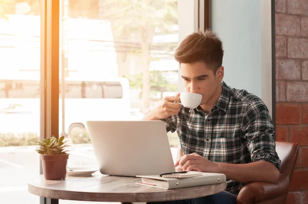 Businessman using laptop with tablet and pen on wooden table in