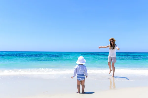 Young adorable mother having fun with little daughter at tropical beach
