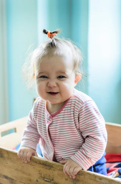 Portrait of adorable little smiling baby girl staying at her bed