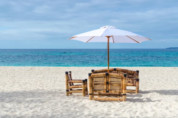 Tropical resort view with beach table, chairs and umbrella on exotic sandy beach