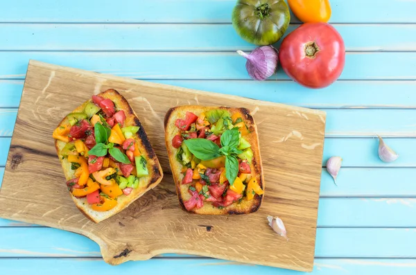 Italian bruschetta with chopped tomatoes and basil on wooden cutting board