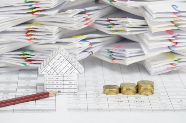 Brown pencil and house with step pile of gold coins