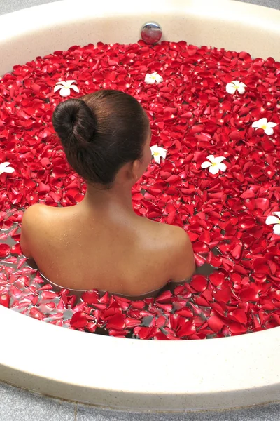 Body care female in bath with rose petal