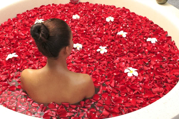 Body care female in bath with rose petal
