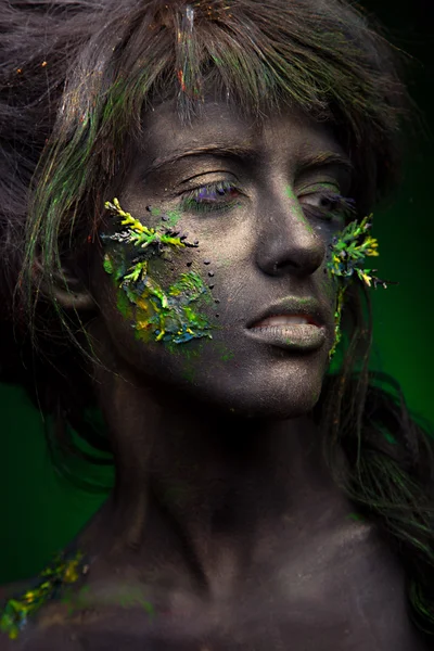 Woman with black face and green face art