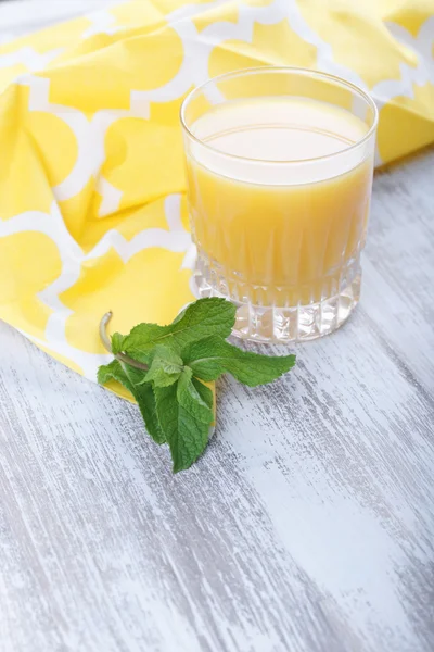 Orange juice and mint leaves on a wooden background
