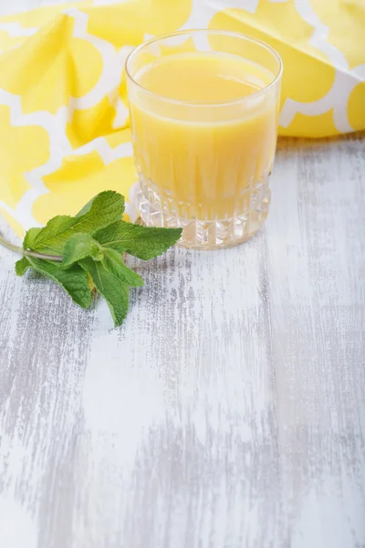Orange juice and mint leaves on a wooden background