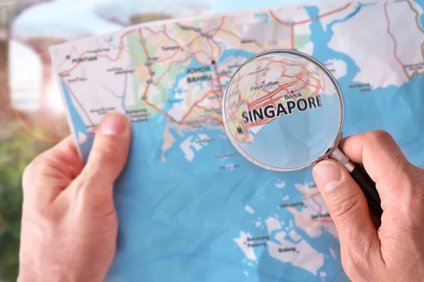 Man consulting a map of Singapore with a magnifying glass