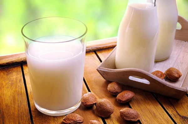 Glass of almond milk on a table with almonds