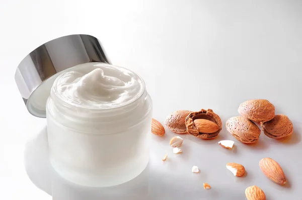 Almond moisturizer jar open with almonds on the table top