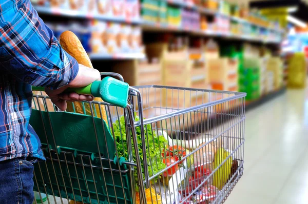 Man pushing shopping cart in the supermarket aisle