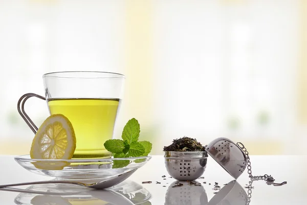 Green tea with mint and lemon with strainer front view