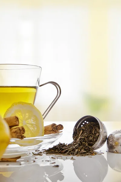 Green tea with cinnamonnd lemon and metallic strainer close up