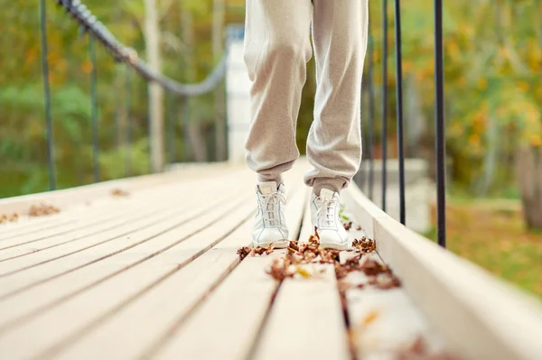 Woman feet in white shoes walking in autumn park