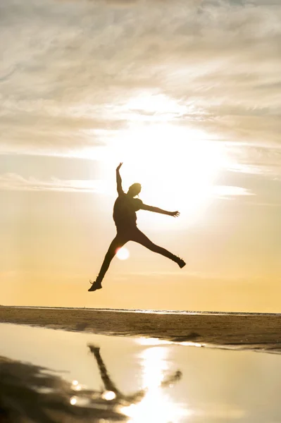 Emotions of jumping girl silhouette in rays of sunlight at sunset.
