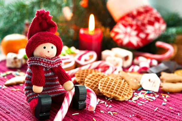 Wooden smiling doll with sweets on christmas background with can
