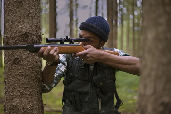 Interracial hunter in the forest aiming at prey