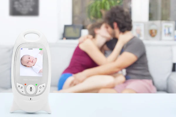 Inattentive babysitter making out not realizing the baby is crying on the monitor