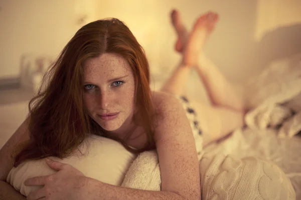 Freckled redhead in a bedroom at Sunset