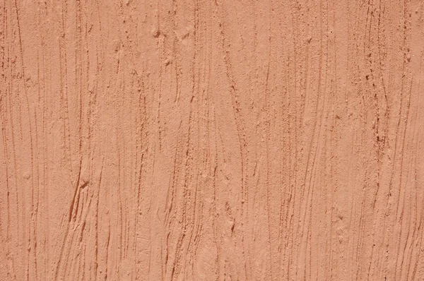 Orange rough plaster on wall closeup in sunny day