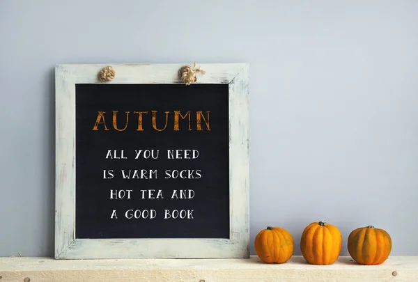 Chalkboard frame on the grey wall with books pumpkins AUTUMN -