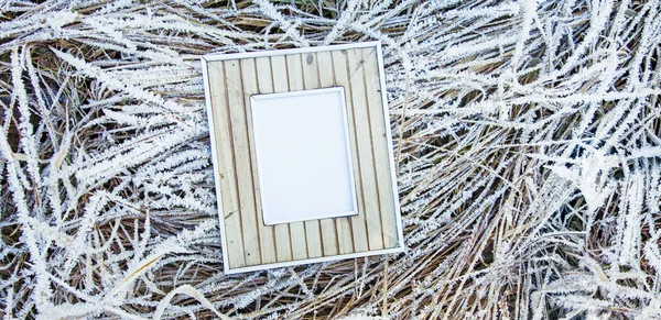 Old wooden frame over frozen grass.