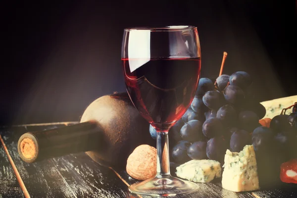 Red wine and grapes on an old shabby wooden background bottle of dusty retro rustic style