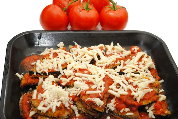 Pan of Eggplant Parmesan with Tomatoes in the Background
