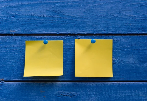 Two yellow stickers on blue wooden wall