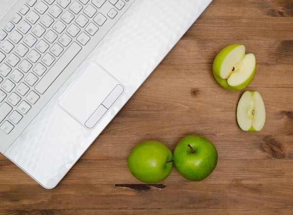 Several green apples and  laptop