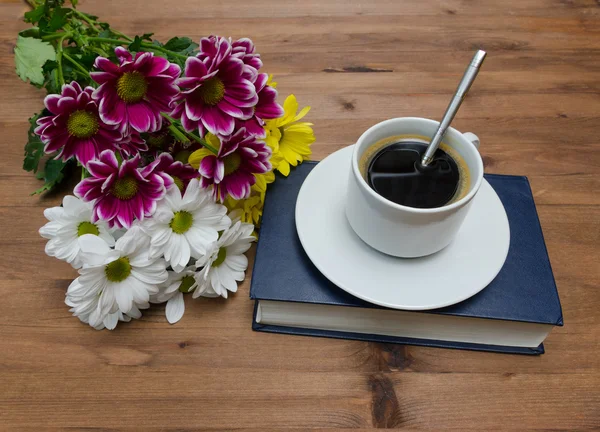 Cup of coffee with flowers and book