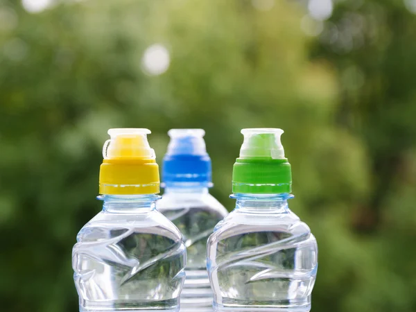 Three Colorful sport plastic water bottle on green background