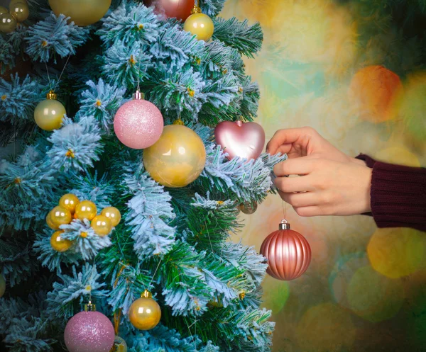 Hands hanging a bauble on christmas tree