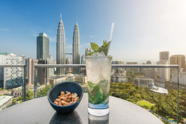 Mojito cocktail and cashews on table in rooftop bar at Kuala Lum